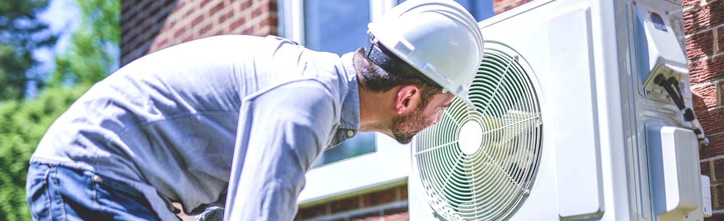 Technician inspecting an outdoor air conditioning unit